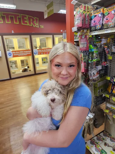 Woman holding a small light-colored puppy in the store